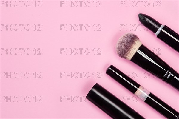 Set of brushes and cosmetic products on a pink background