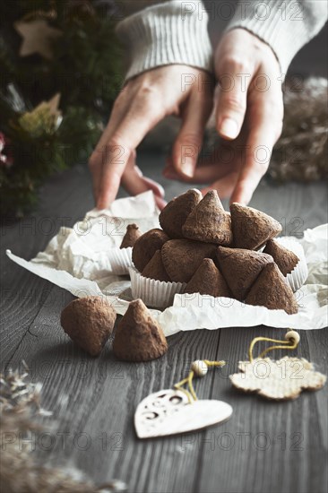 Simple Christmas truffle candy on a wooden background with plant branches