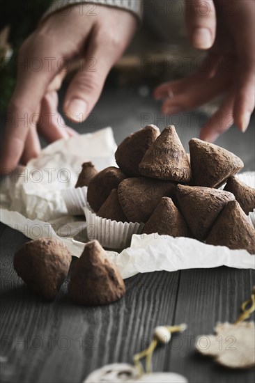 Simple Christmas truffle candy on a wooden background with plant branches