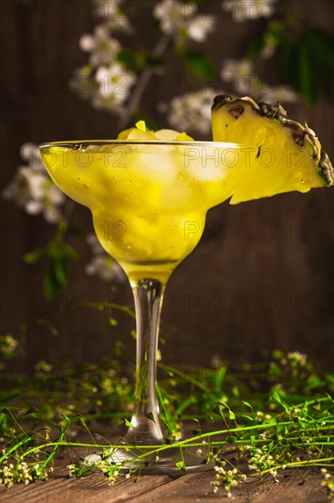 Pineapple fruit soft drink with ice on a wooden background with flowers