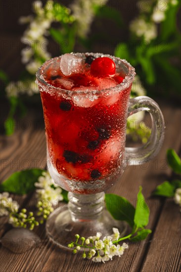 Berry soft drink with ice on a wooden background with flowers