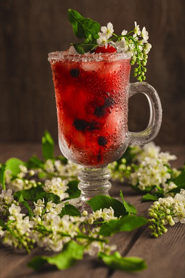 Berry soft drink with ice on a wooden background with flowers