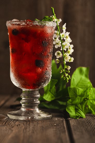 Berry soft drink with ice on a wooden background with flowers