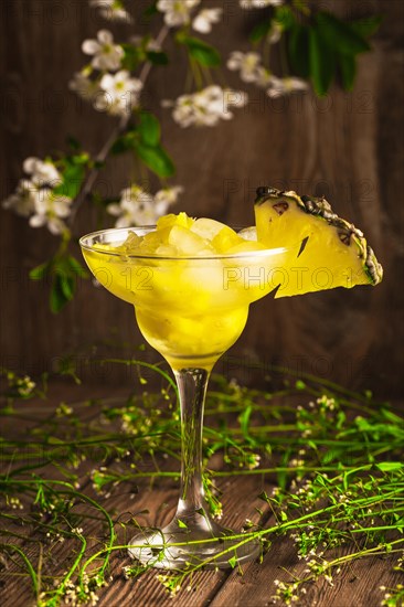 Pineapple fruit soft drink with ice on a wooden background with flowers