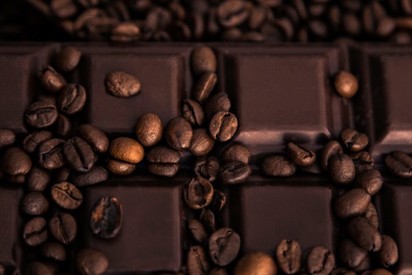 Roasted coffee beans and chocolate bar close-up