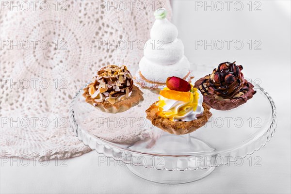 Tasty cakes on a transparent plate on a background of a white tablecloth