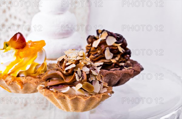 Tasty cakes on a transparent plate on a background of a white tablecloth