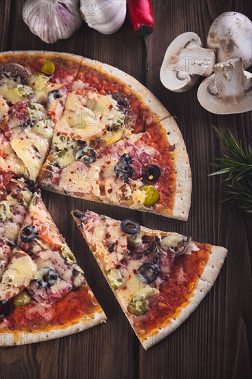 Sliced tasty fresh pizza with mushrooms and sausage on a wooden background. View from above. Close-up