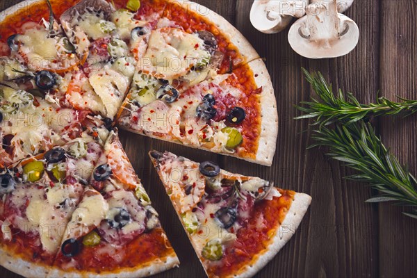 Sliced tasty fresh pizza with mushrooms and sausage on a wooden background. View from above. Close-up