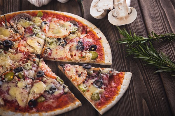 Sliced tasty fresh pizza with mushrooms and sausage on a wooden background. View from above. Close-up