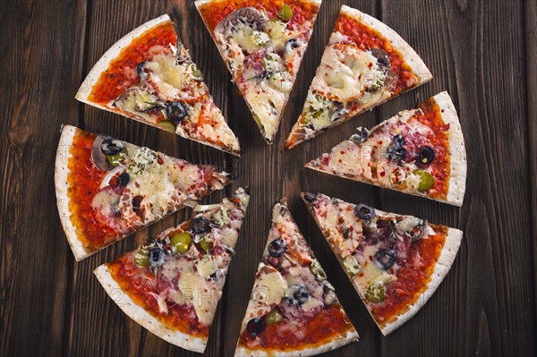 Sliced tasty fresh pizza with mushrooms and sausage on a wooden background. View from above. Close-up