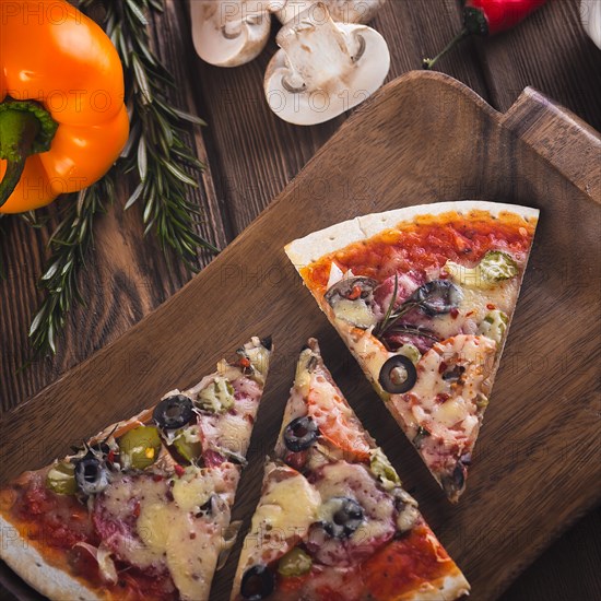 Sliced tasty fresh pizza with mushrooms and sausage on a wooden background. View from above. Close-up