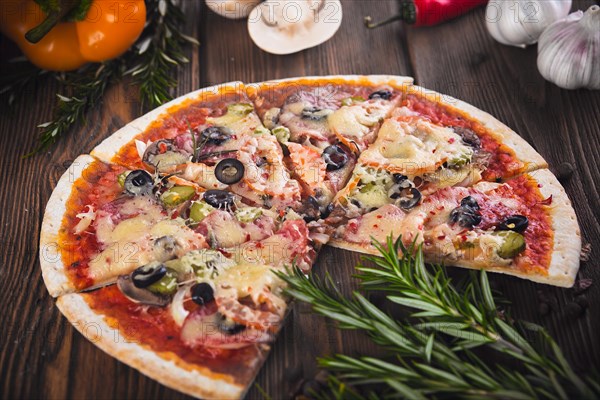 Sliced tasty fresh pizza with mushrooms and sausage on a wooden background. View from above. Close-up