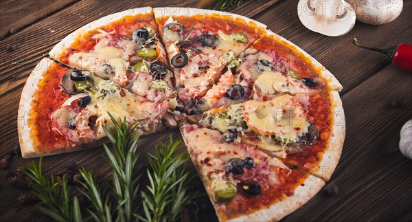 Sliced tasty fresh pizza with mushrooms and sausage on a wooden background. View from above. Close-up