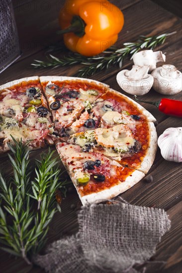 Sliced tasty fresh pizza with mushrooms and sausage on a wooden background. View from above. Close-up