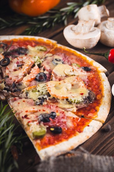 Sliced tasty fresh pizza with mushrooms and sausage on a wooden background. View from above. Close-up