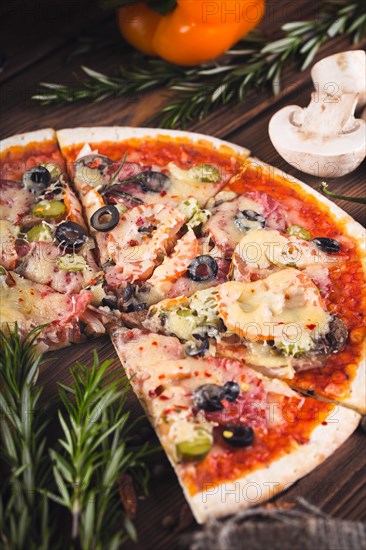 Sliced tasty fresh pizza with mushrooms and sausage on a wooden background. View from above. Close-up