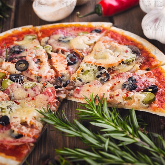 Sliced tasty fresh pizza with mushrooms and sausage on a wooden background. View from above. Close-up