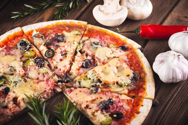 Sliced tasty fresh pizza with mushrooms and sausage on a wooden background. View from above. Close-up