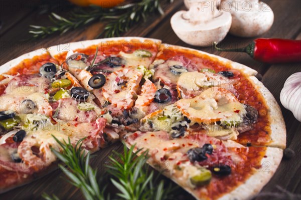 Sliced tasty fresh pizza with mushrooms and sausage on a wooden background. View from above. Close-up