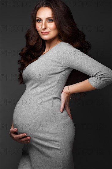 Beautiful pregnant woman in a gray dress
