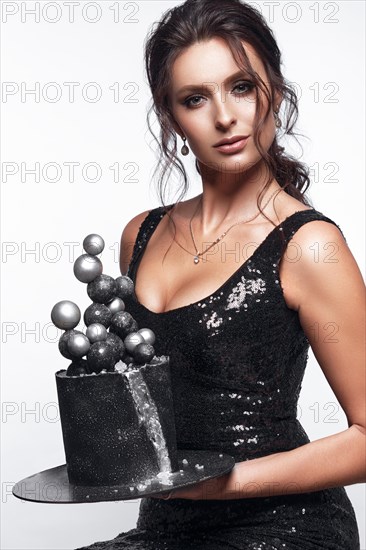 Beautiful woman pastry chef in a short black dress with a cake in her hands