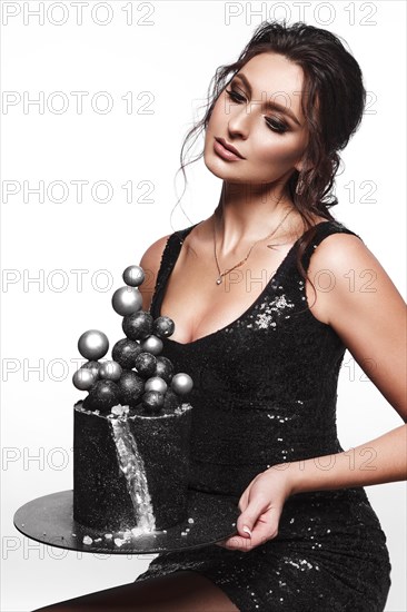 Beautiful woman pastry chef in a short black dress with a cake in her hands