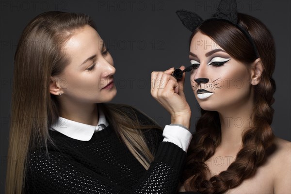 Two beautiful girls on a photo shoot to apply makeup to the face. Beauty fashion model. Photos shot in studio