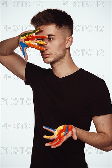 A young man with multi-colored paint on his hands. Hairdresser colorist or artist