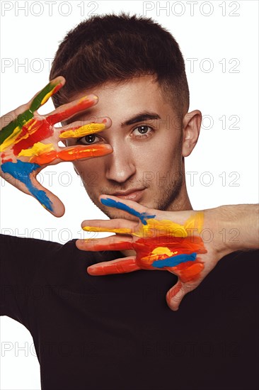 A young man with multi-colored paint on his hands. Hairdresser colorist or artist