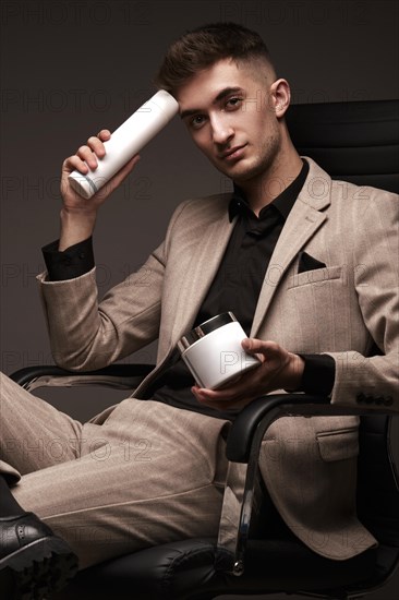 Handsome man hairdresser in a suit with a cosmetic in his hands. Photo taken in the studio