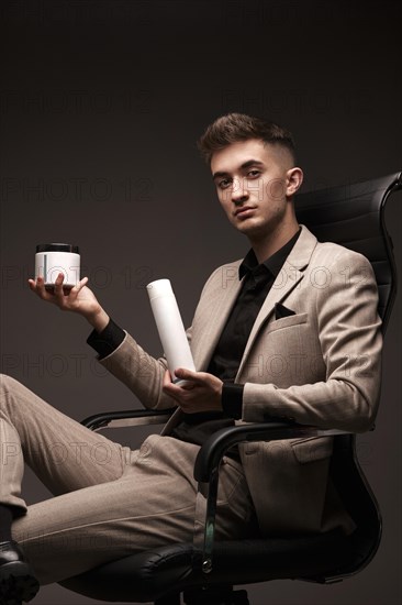 Handsome man hairdresser in a suit with a cosmetic in his hands. Photo taken in the studio