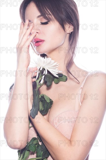 Beautiful sexy girl in lingerie-type bodice with delicate make-up and flower in hand. The beauty of the face. Photos shot in the studio on a white background