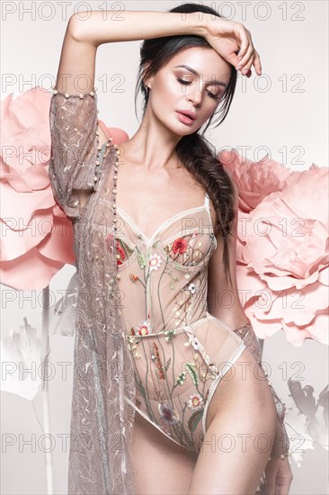 Beautiful girl with classic make-up and hairstyle in delicate Underwear with large flowers on background. beauty face. Photos shot in studio