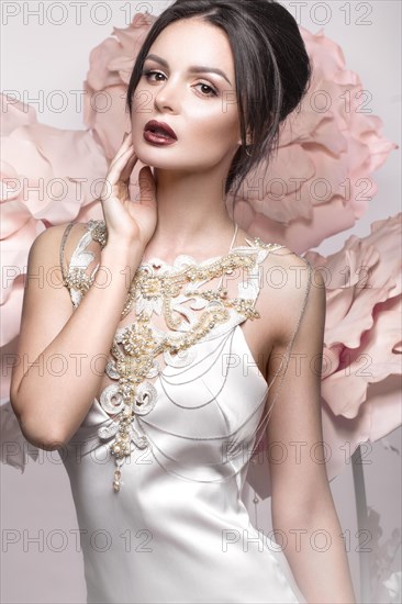 Beautiful girl with classic make-up and hairstyle in delicate Underwear with large flowers on background. beauty face. Photos shot in studio