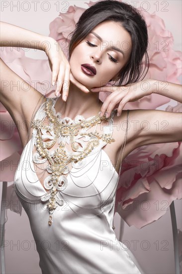 Beautiful girl with classic make-up and hairstyle in delicate Underwear with large flowers on background. beauty face. Photos shot in studio