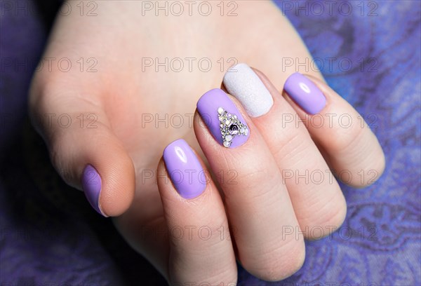 Beautiful purple manicure with crystals on female hand. Close-up. Picture taken in the studio