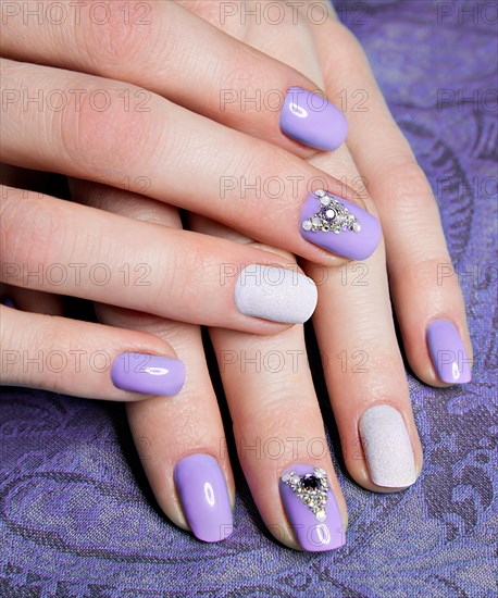 Beautiful purple manicure with crystals on female hand. Close-up. Picture taken in the studio