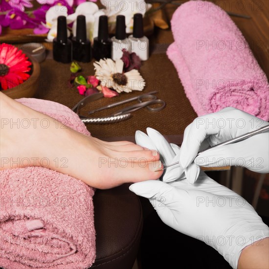 Closeup finger nail care by pedicure specialist in beauty salon. Pedicurist clear cuticle professional scissors for manicure and pedicure