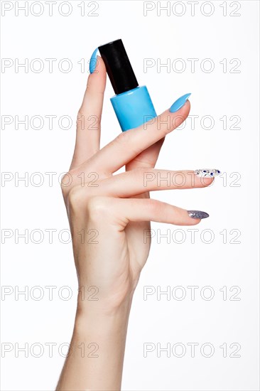 Beautiful summer blue manicure on female hand with nail polish. Close-up. Picture taken in the studio