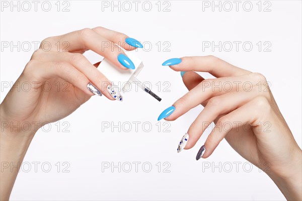Beautiful summer blue manicure on female hand with oil for cuticles