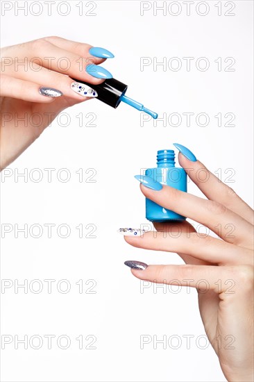 Beautiful summer blue manicure on female hand with nail polish. Close-up. Picture taken in the studio