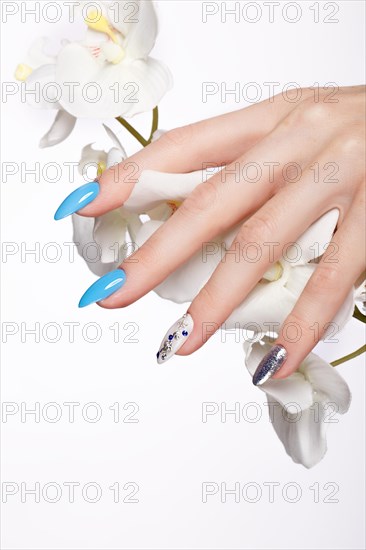 Beautiful summer blue manicure on female hand with flowers. Close-up. Picture taken in the studio