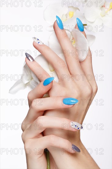 Beautiful summer blue manicure on female hand with flowers. Close-up. Picture taken in the studio