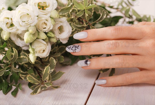 Gentle neat manicure on female hands on a background of flowers. Nail design