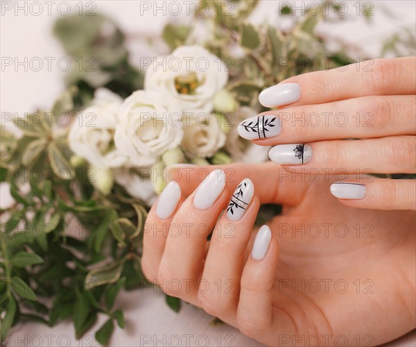 Gentle neat manicure on female hands on a background of flowers. Nail design