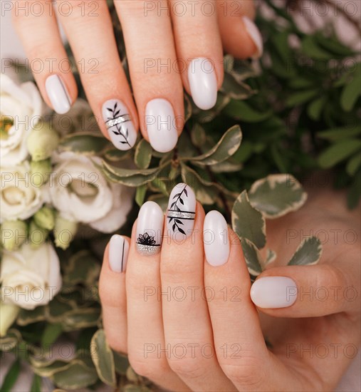 Gentle neat manicure on female hands on a background of flowers. Nail design