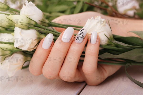 Gentle neat manicure on female hands on a background of flowers. Nail design