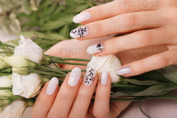 Gentle neat manicure on female hands on a background of flowers. Nail design