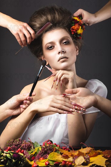 Beautiful girl in autumn image with long nails with bright and unusual make-up. Picture taken in the studio on a gray background